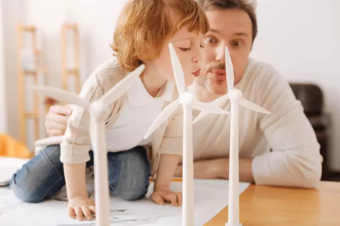 un enfant souffle sur une éolienne miniature